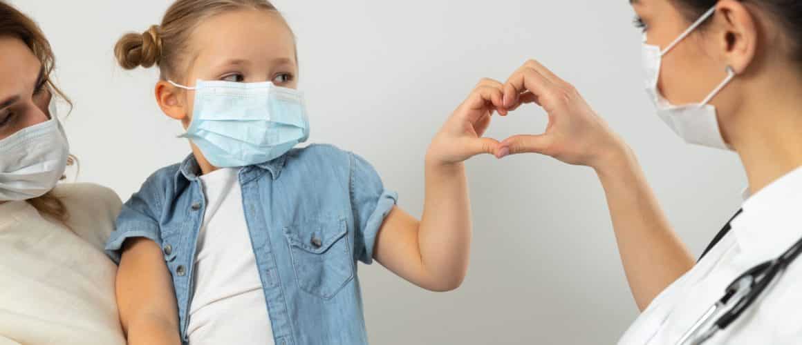 Female pediatrician making heart with hands with her little patient stock photo. Pediatrics concept